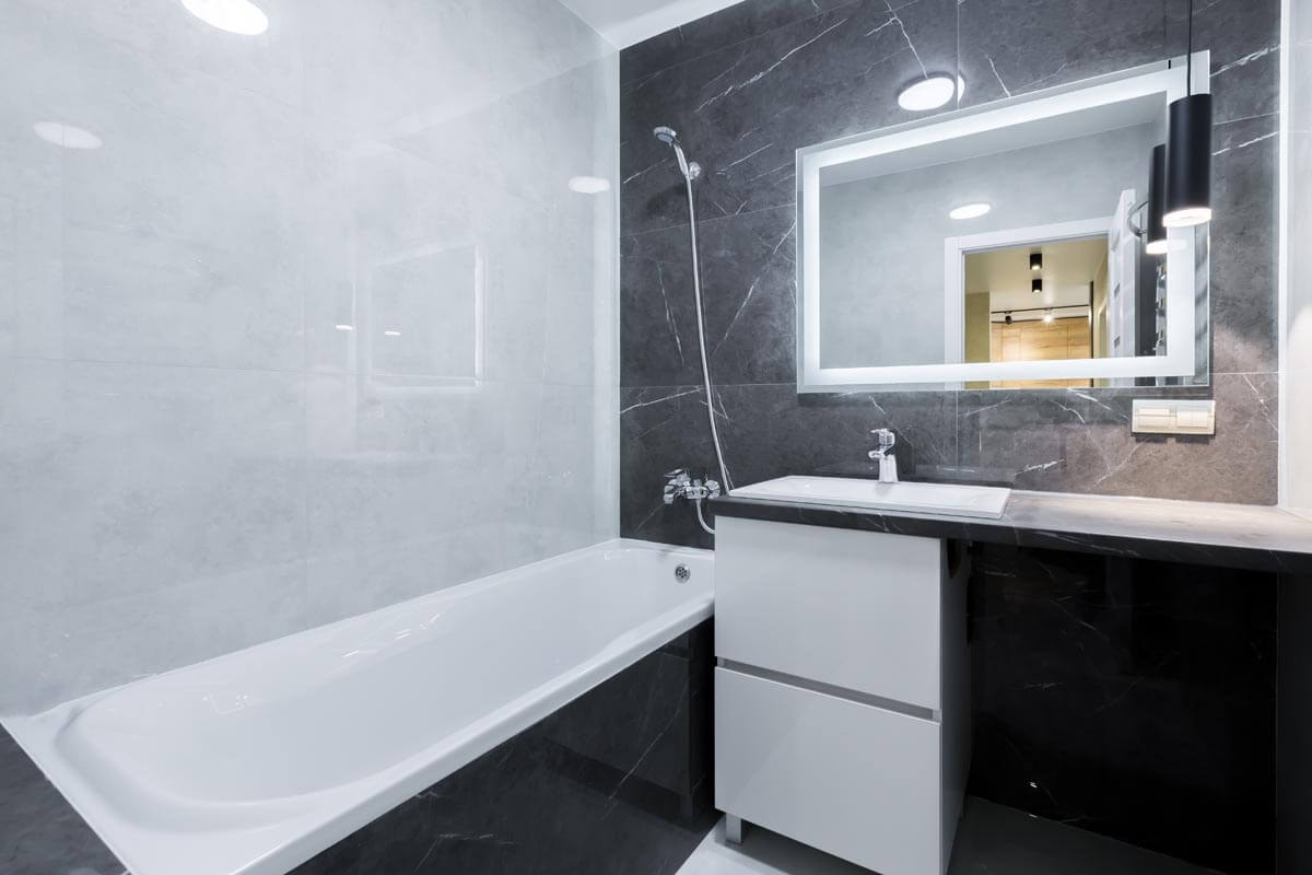 Small, modern black-and-white bathroom with a combined shower and bathtub, and a washbasin with a large mirror above it