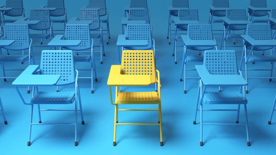 View of a blue room filled with blue chairs with small tables and a single yellow chair with a small table in the centre.
