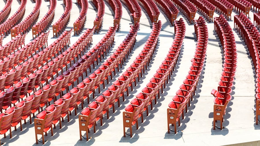 Overhead view of a large group of red folding seats in a vast concert hall or arena.