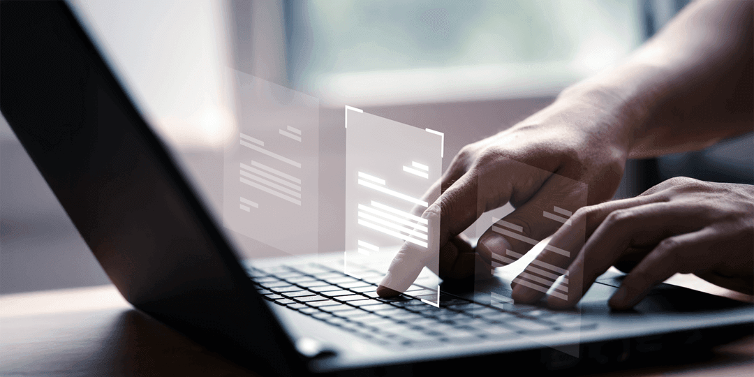 Close-up of hands typing on a laptop keyboard; two floating document symbols digitally overlaid.