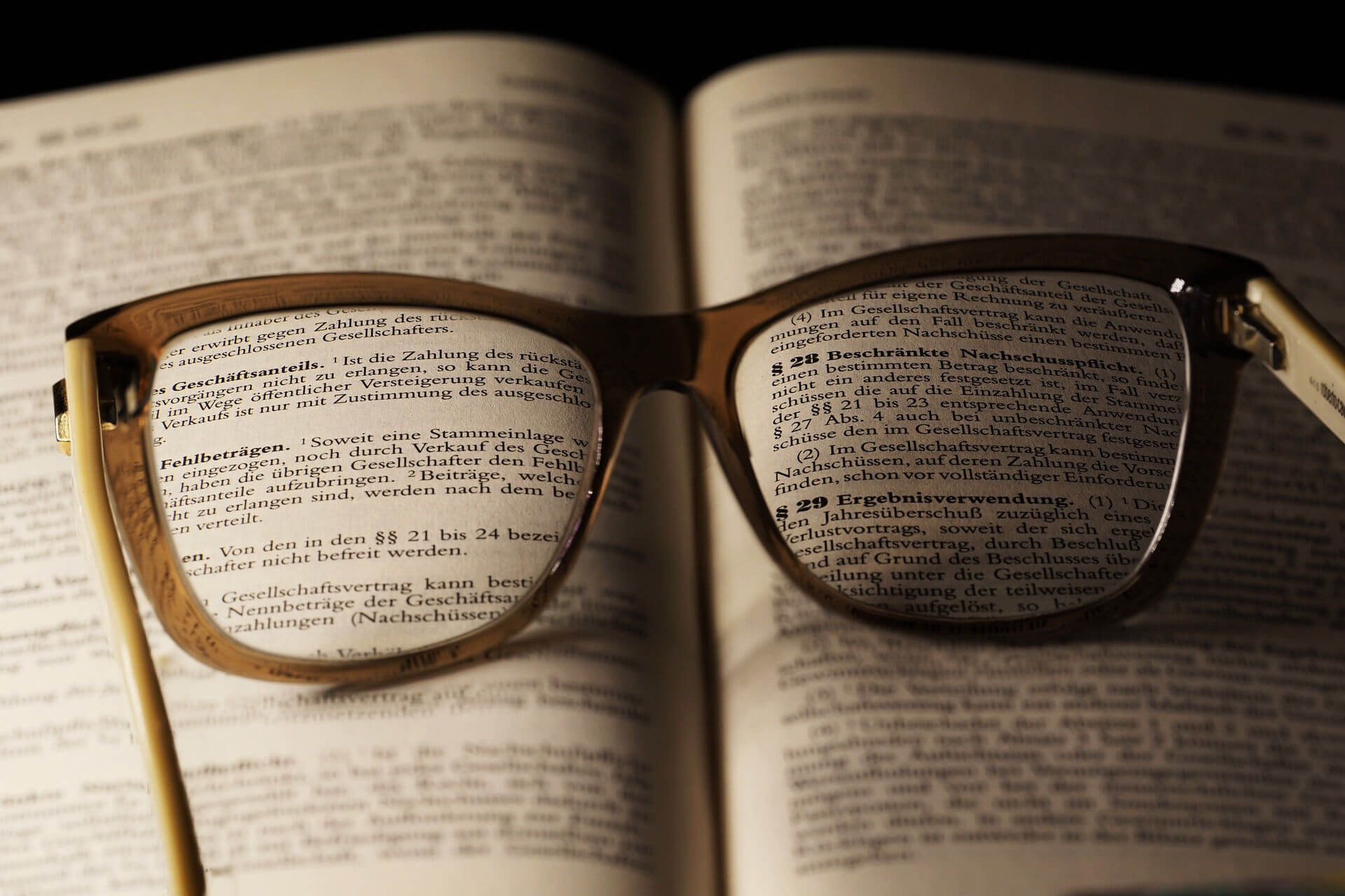 Close-up of a book of legal texts with an open pair of glasses resting on top, making some of the text easier to read.
