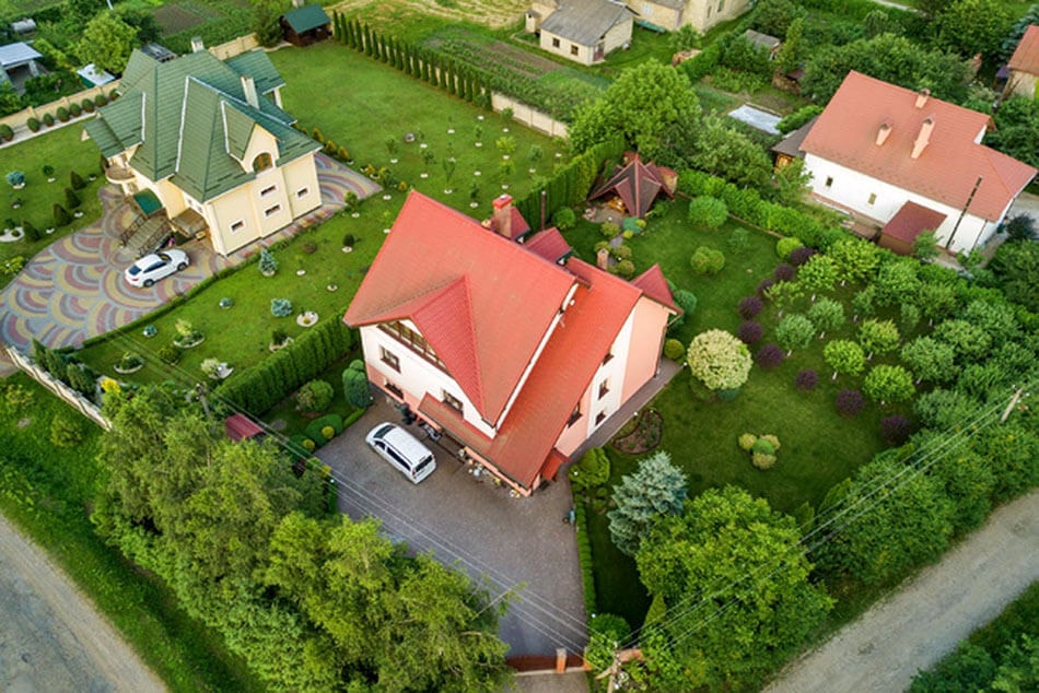 Photo taken from above at an angle of a multi-story apartment building with lush greenery around it and two upscale neighboring buildings