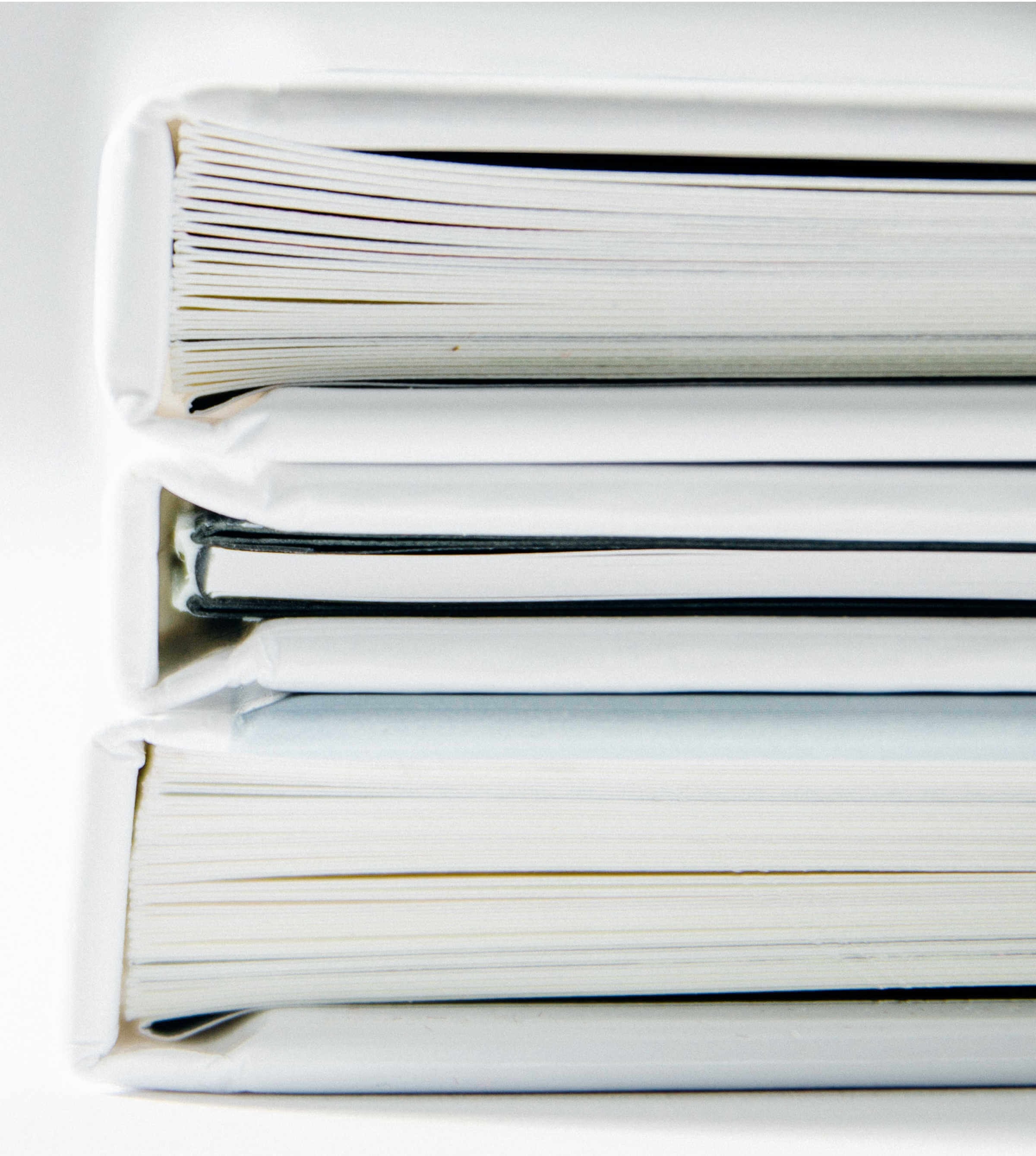 Close-up of the spines of three thin books stacked on their sides on top of each other.