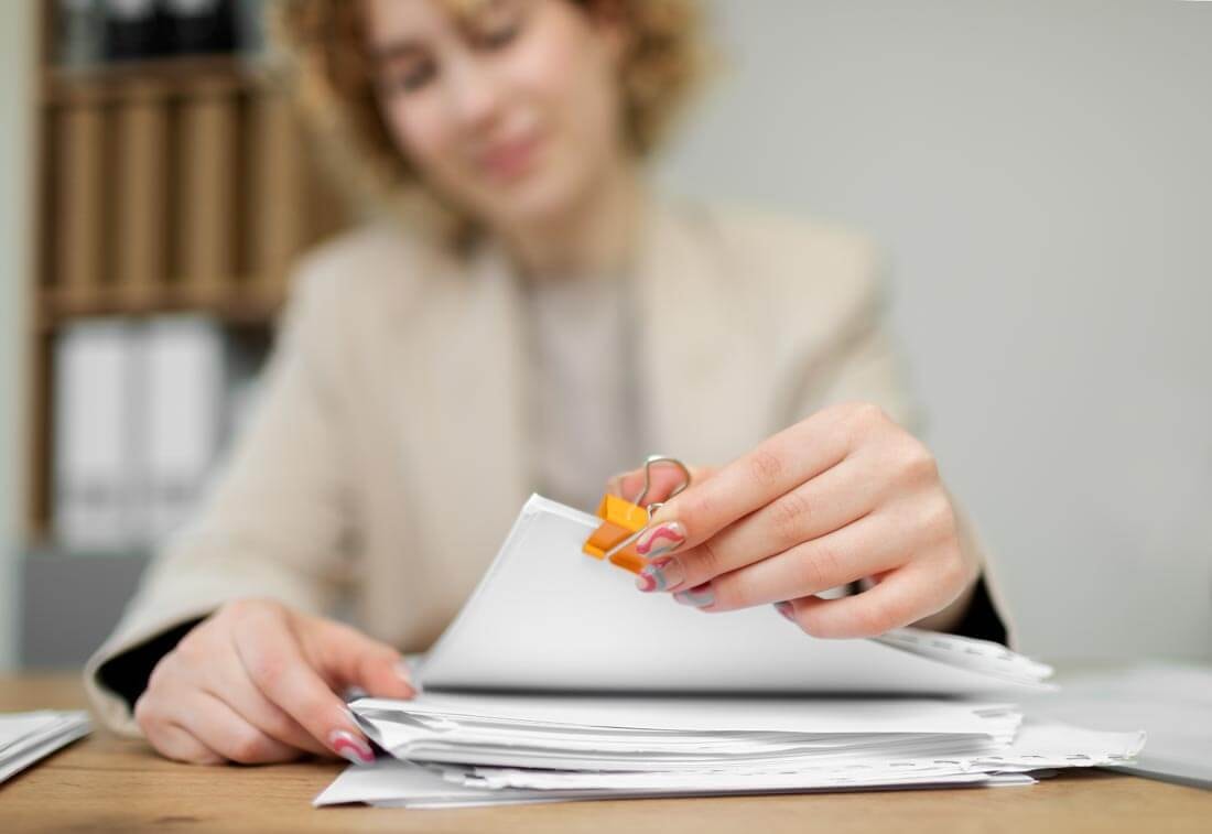 Close-up of a real estate agent taking a stapled set of documents from the top of a stack of papers