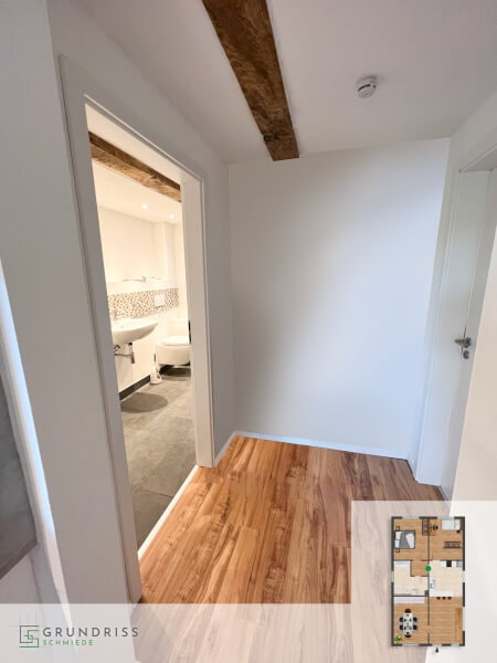Photo of a hallway with a view through an open door into a modern bathroom, with a ground-floor plan in the lower right corner highlighting the hallway area.