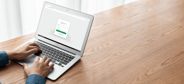 Hands typing on a laptop keyboard, with the Grundriss Schmiede website displayed on the screen