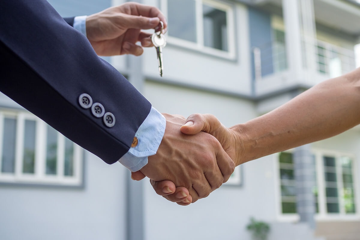 Handshake during a house key handover in front of a property