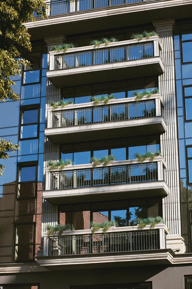 Projecting balconies with black railings are visible on the glass facade of a multi-story building