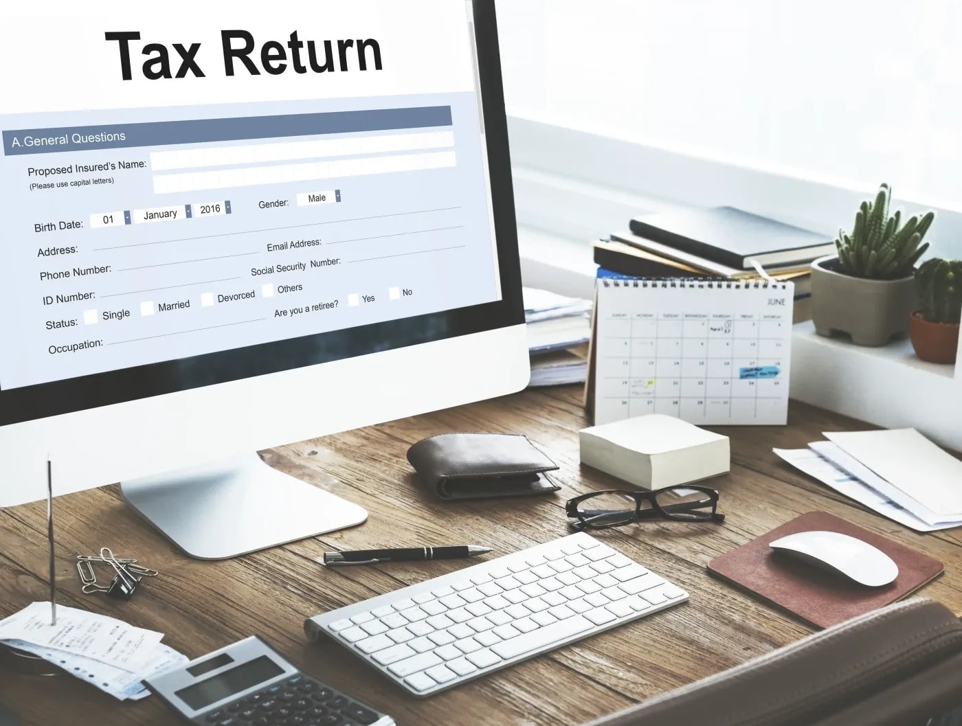 Close-up of a desk with office supplies and a PC, its monitor showing an app for calculating tax refunds