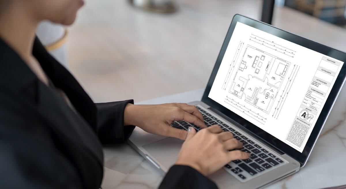 Woman looking at a dimensioned floor plan on a laptop with her hands on the keyboard.