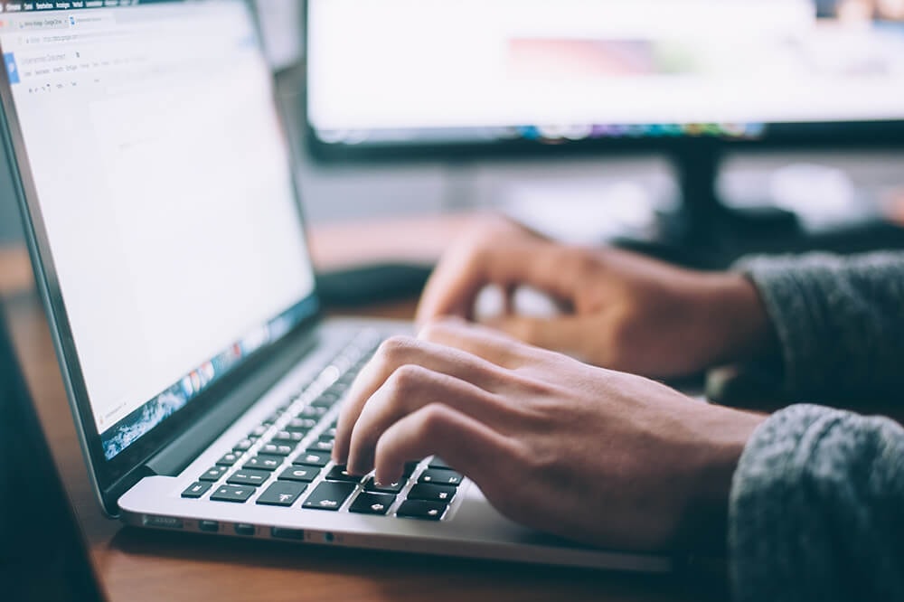 Close-up of hands on a laptop keyboard at a desk