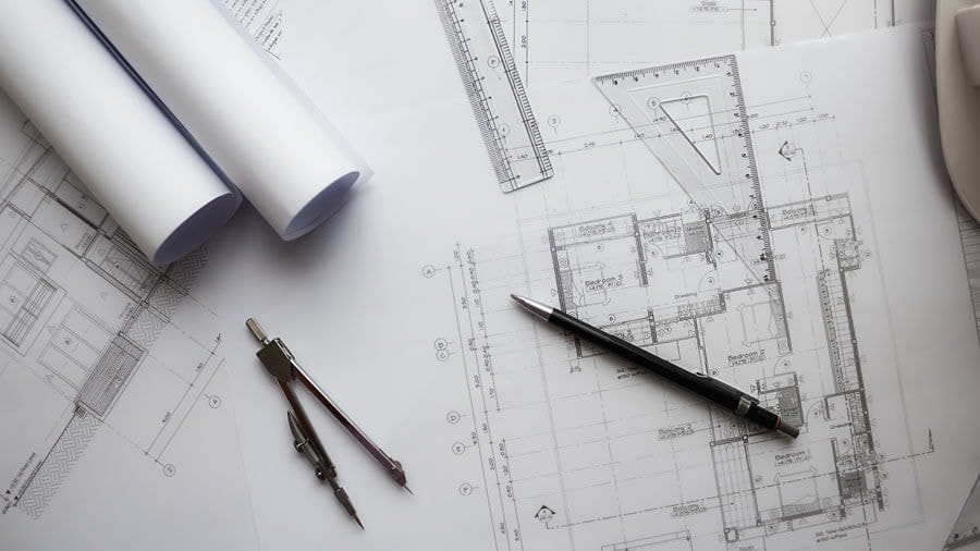 Top view of a floor plan with several technical drawing instruments laid on top of it.