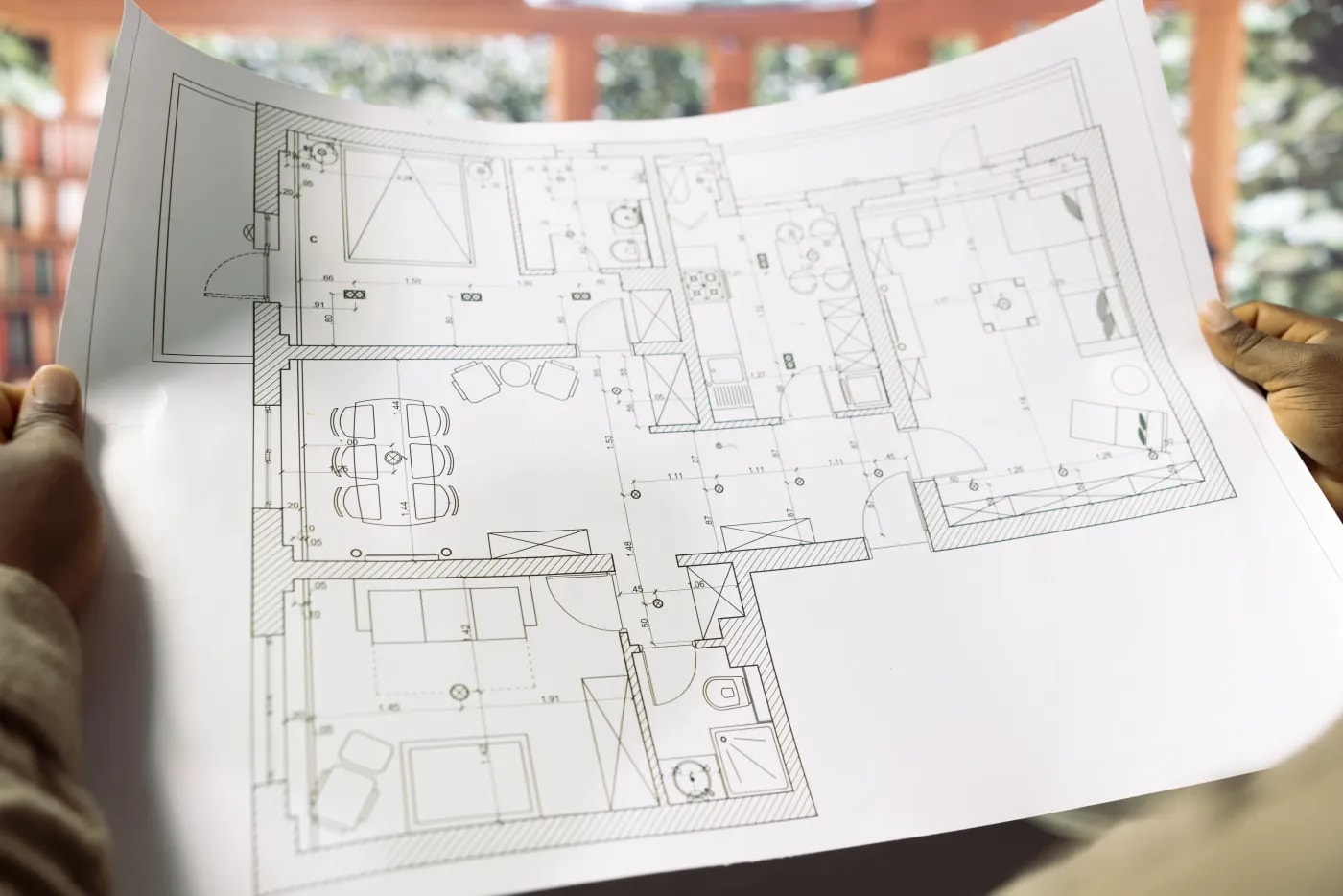A person holding the floor plan of a 4-room apartment with an open dining area.