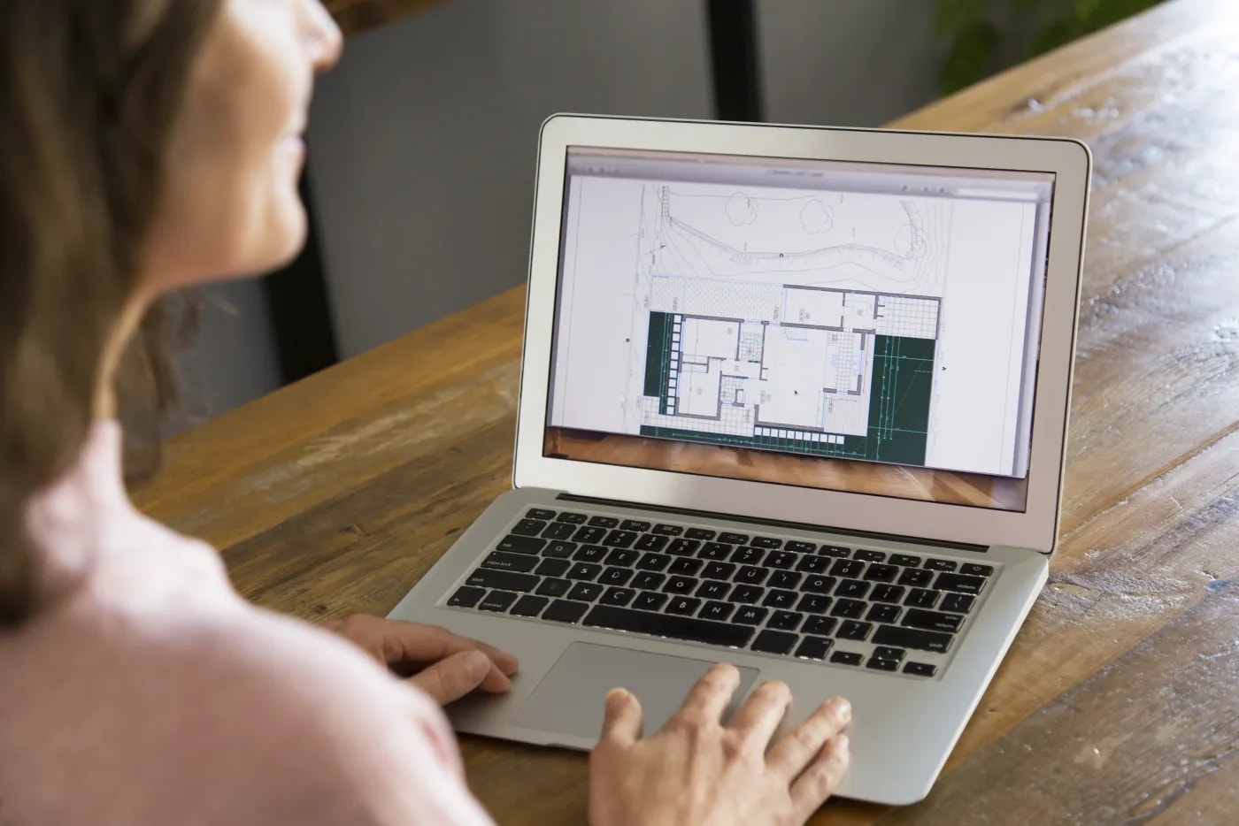 Rear view: a woman at a laptop with a construction drawing on the screen
