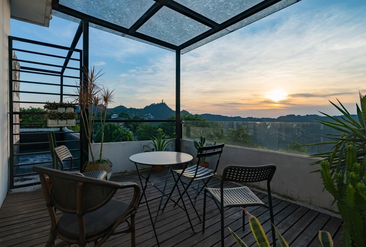 Seating area and plants on a terrace with an acrylic roof, in a sunset atmosphere
