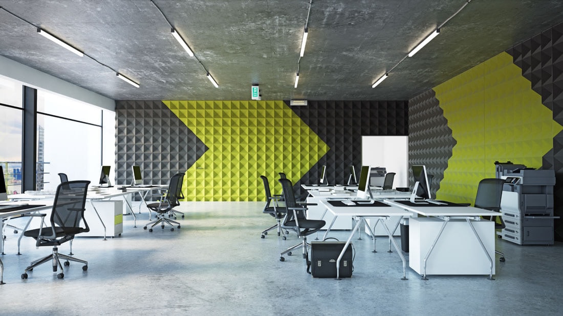 View of an open-plan office with 12 workstations, a printer on the right wall and windows on the left, along with a striking yellow arrow pattern on the wall.