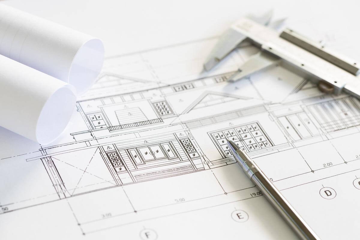 Close-up of a facade drawing with dimensions, with a ballpoint pen and a caliper resting on it