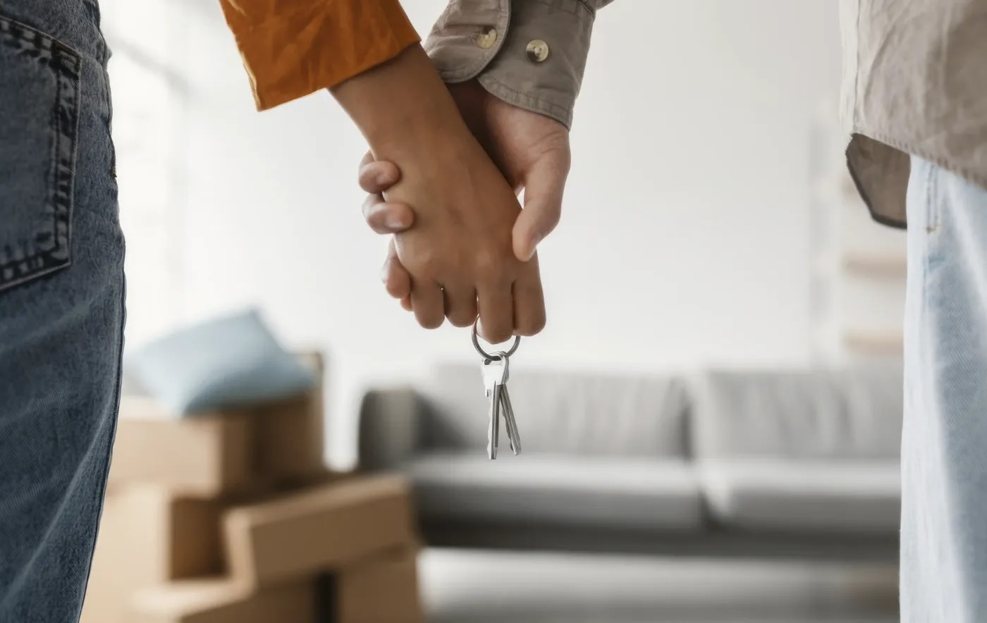 Close-up of a couple's intertwined hands holding an apartment key