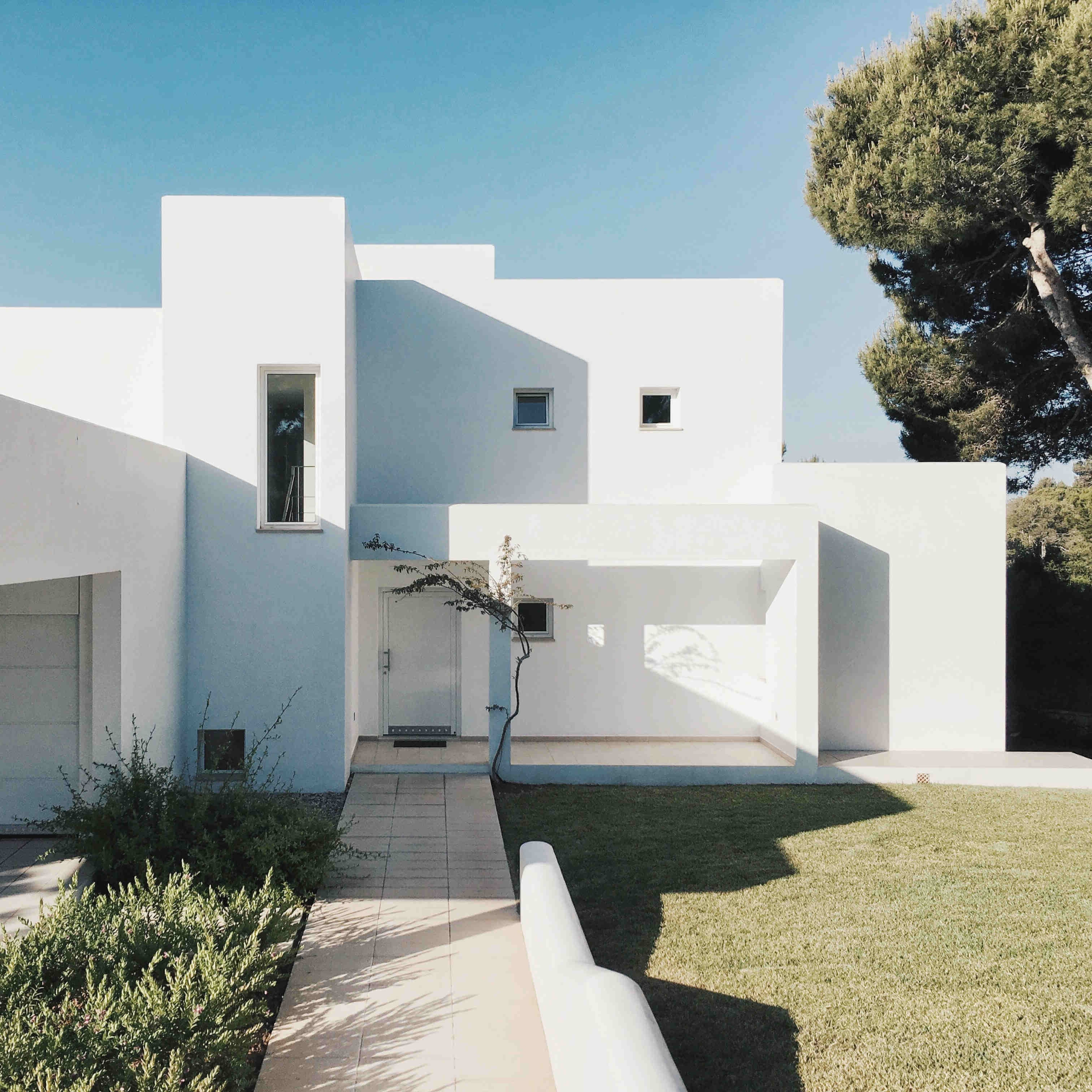 White modern single-family house with a flat roof, garage and multiple balconies.