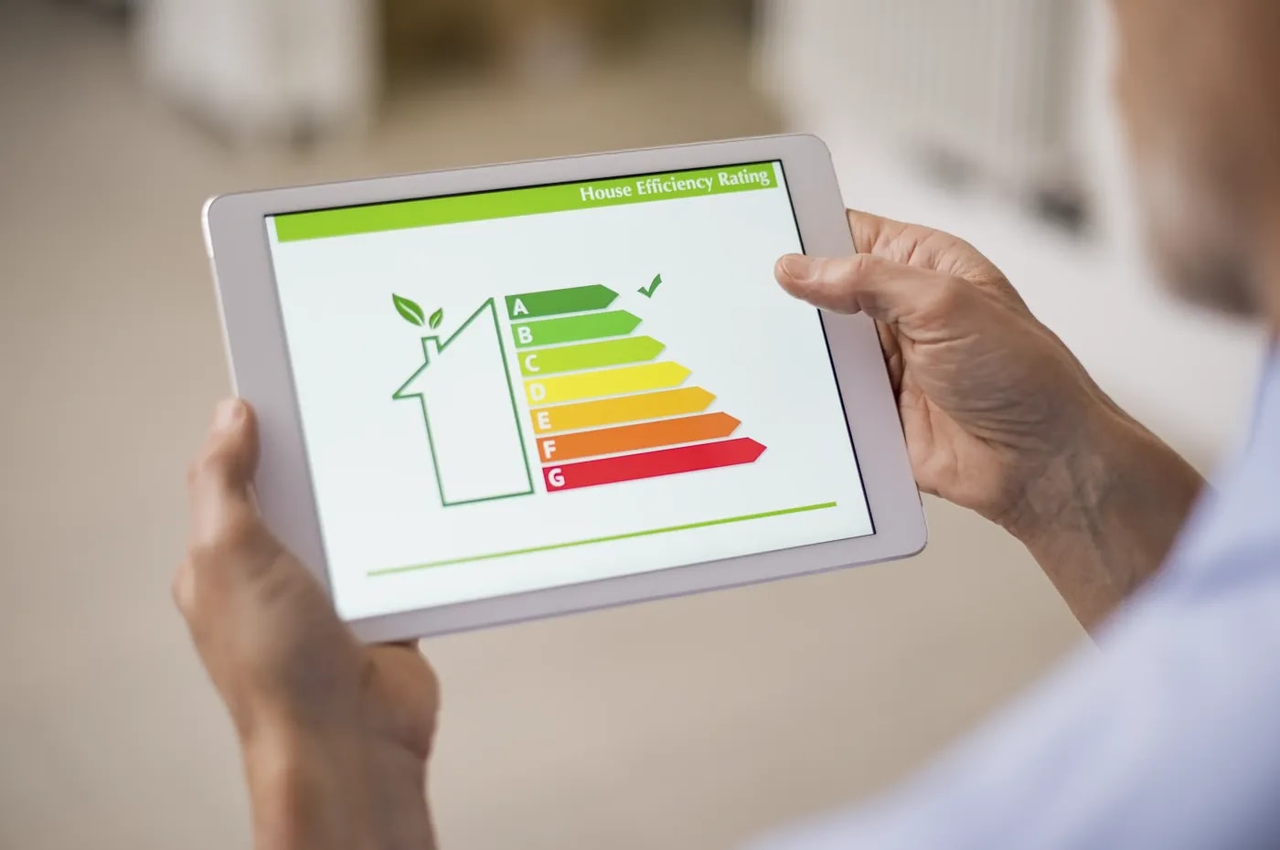 A person holding a tablet displaying a schematic representation of the energy efficiency classes.