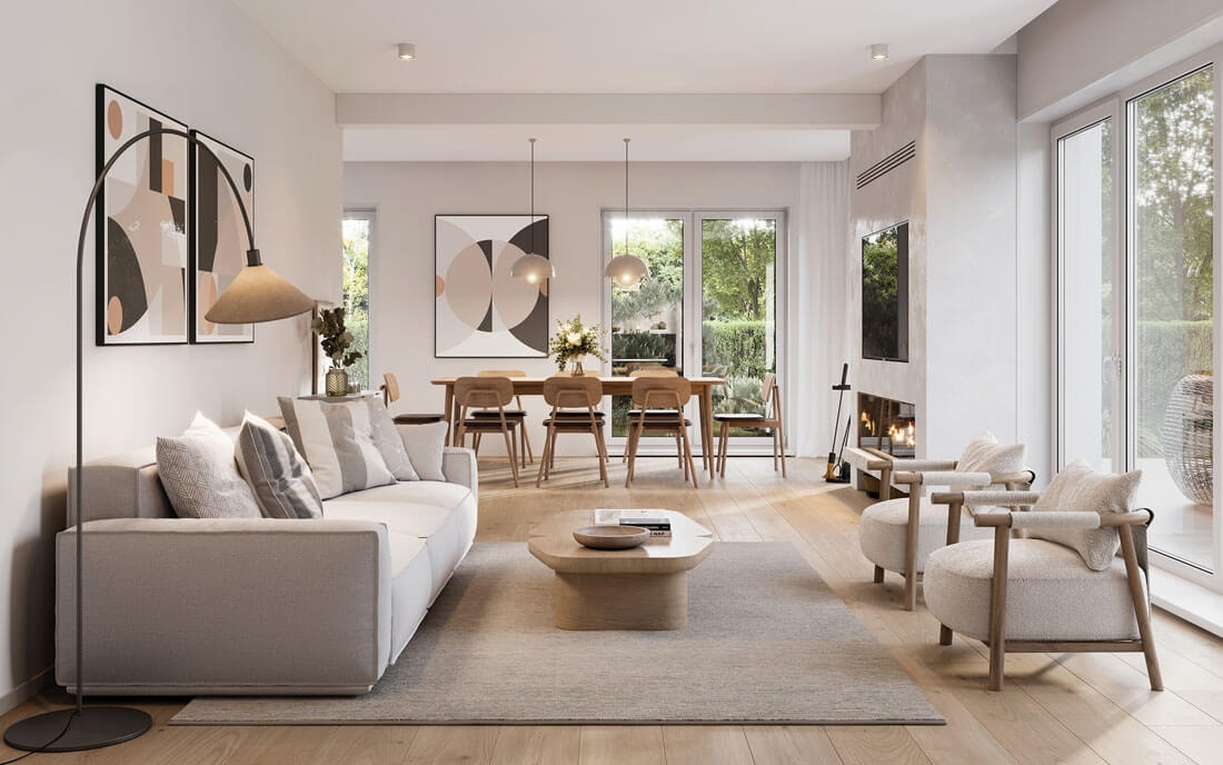 Elegant open-plan living and dining area in warm beige and natural tones with a grey sofa, round wooden coffee table, two armchairs, dining table, art prints, fireplace and large windows overlooking the garden.