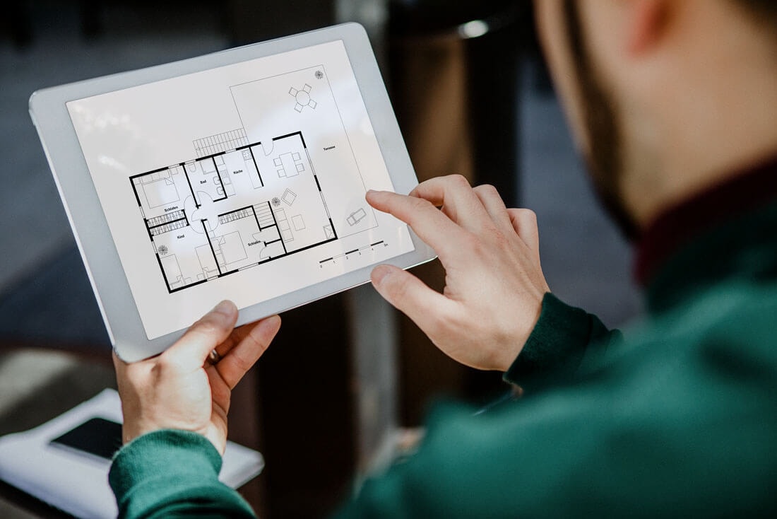 View over the shoulder of a man holding up a tablet, using his right hand to try to swipe something on the screen