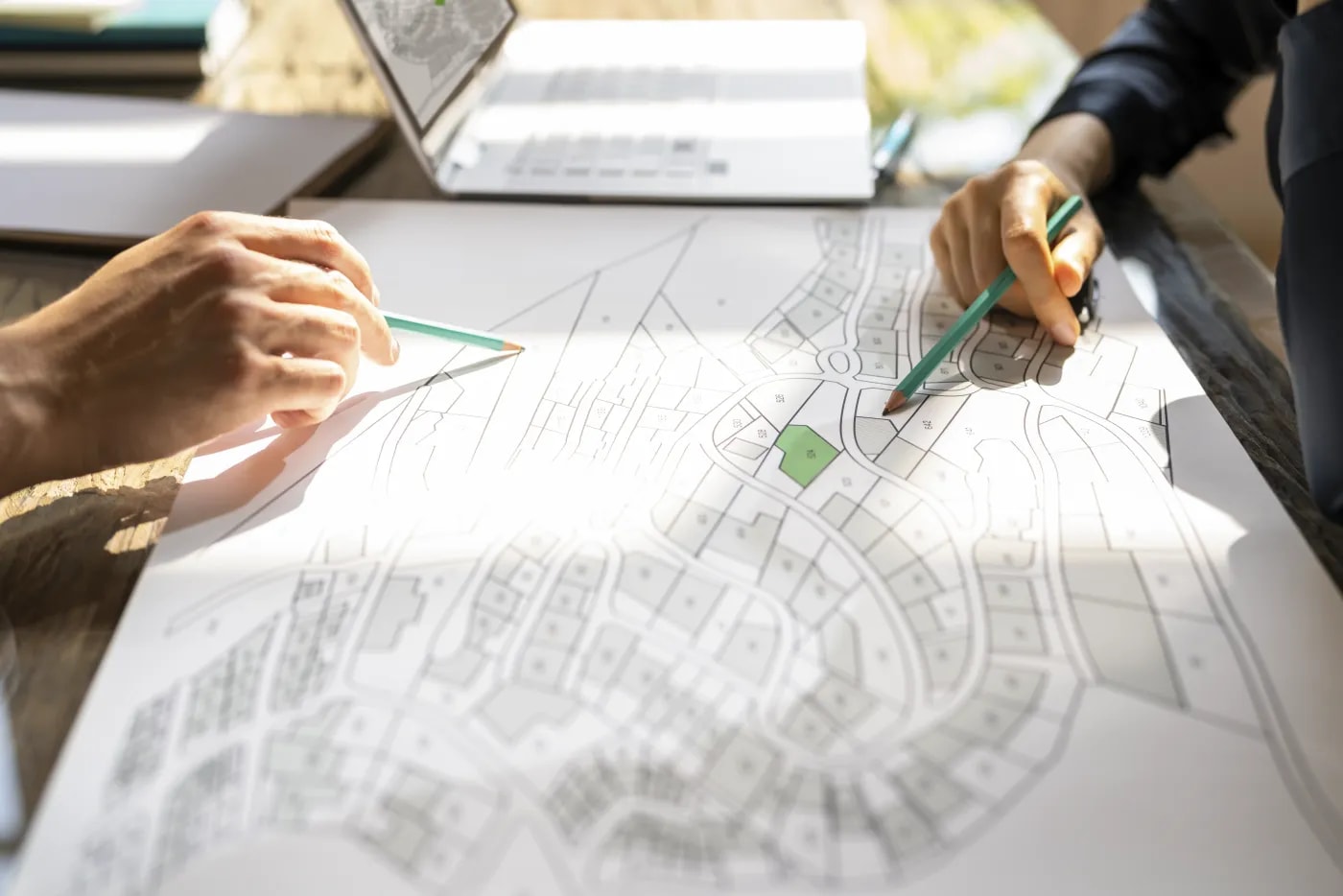 Two people sit at a site plan discussing the location's features while pointing out various details on the plan