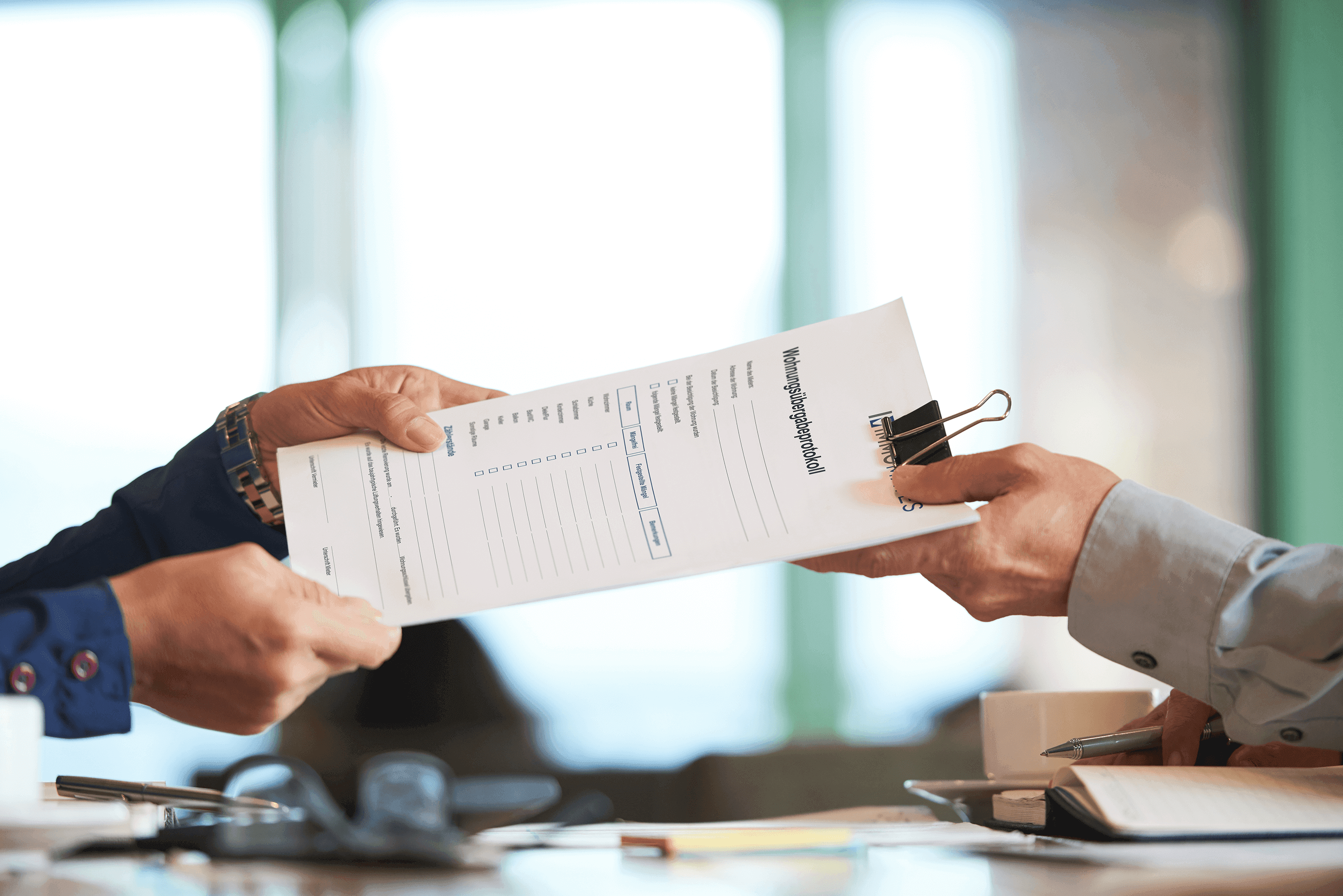 Close-up of someone handing over an empty property handover protocol stapled together with a clip.