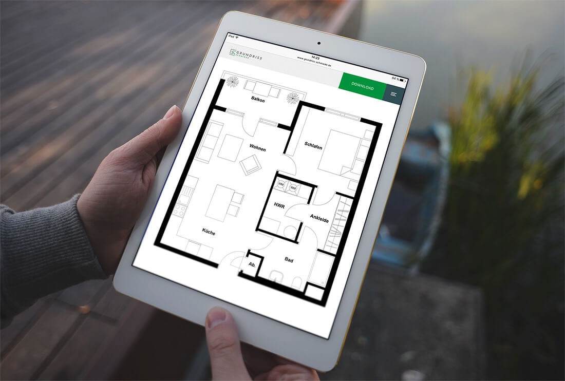 A person holds a tablet showing the floor plan of a 2-room apartment with an open kitchen, utility room, separate dressing room, and balcony