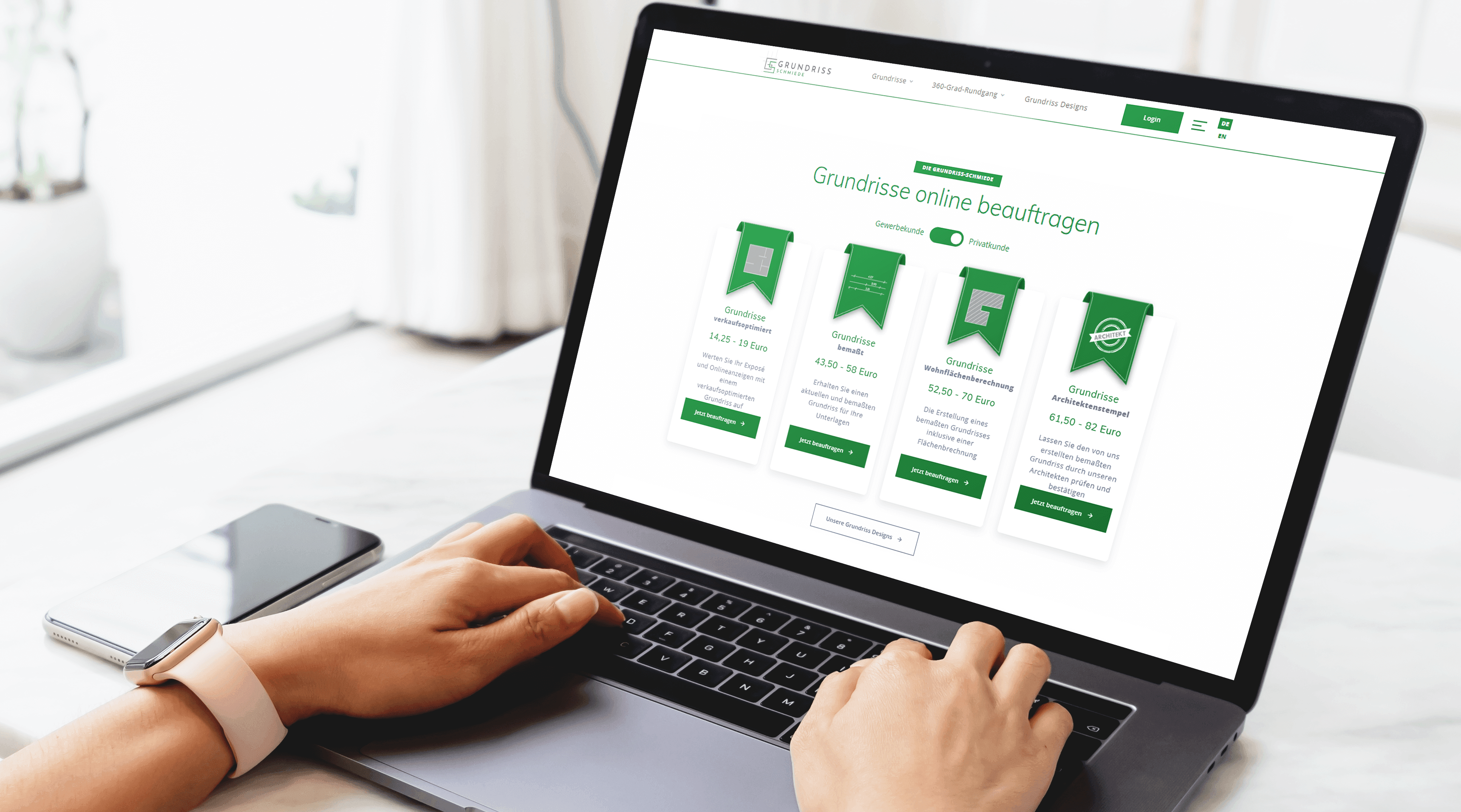 Over-the-shoulder view of a person sitting at a laptop visiting the Grundriss Schmiede website and browsing the range of services.