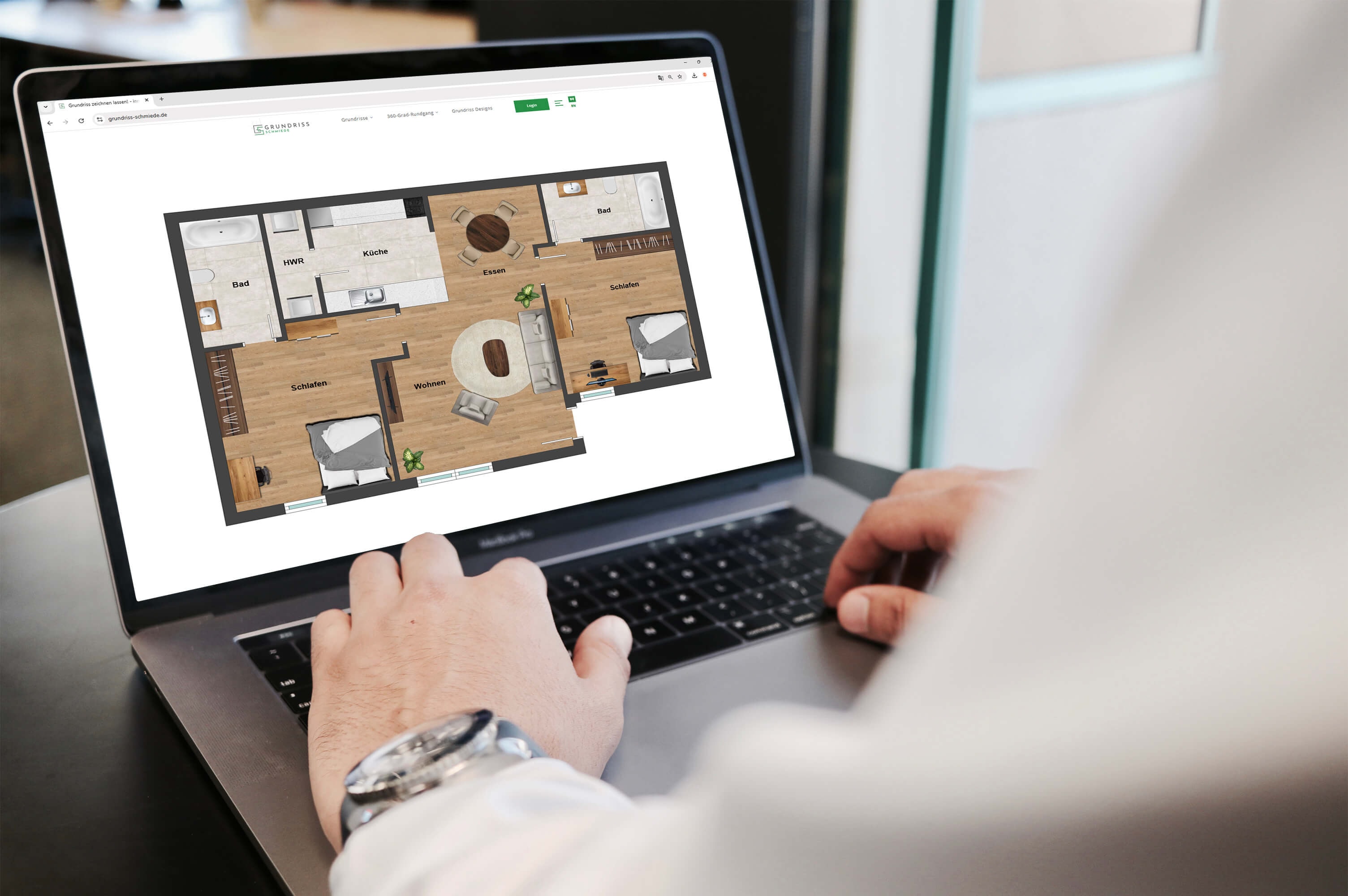 View past a man's arm to the screen of a laptop showing the modern floor plan of a 2.5-room apartment with an open living and dining area, open kitchen and a utility room.