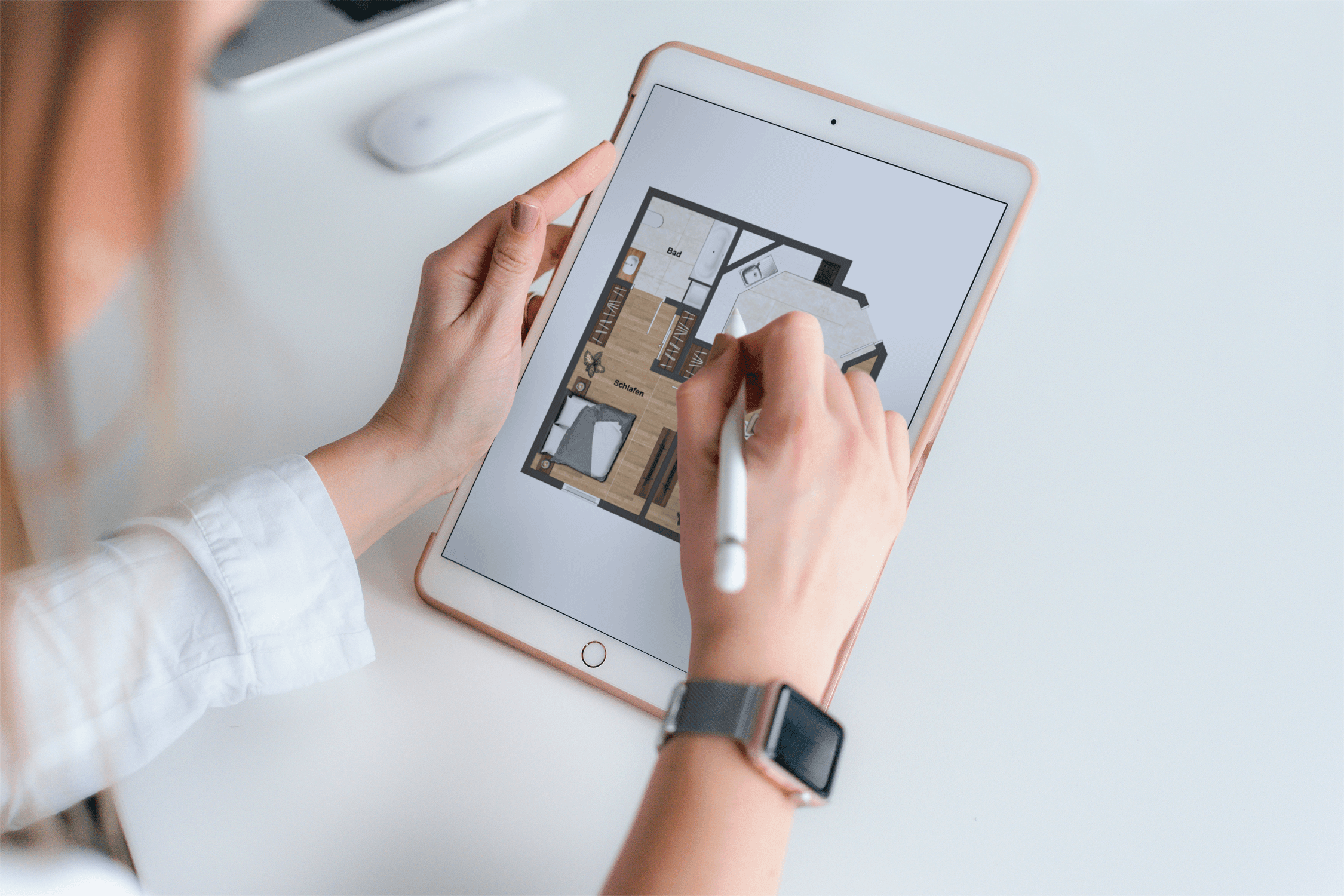 Over-the-shoulder view of a graphic designer editing the floor plan of a 2-room apartment with open kitchen on a tablet using a stylus.