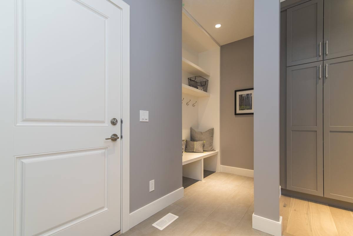 Angled interior hallway with laminate flooring and light grey walls, a coat rack on the left and a built-in wardrobe on the right.