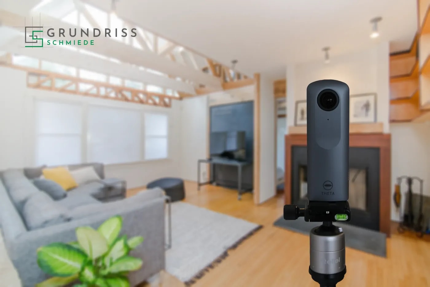Scharf im Vordergrund ist eine 360 Grad Kamera zu sehen, dahinter etwas verschwommen ein modernes Wohnzimmer mit Laminat und elektrischem Kamin.