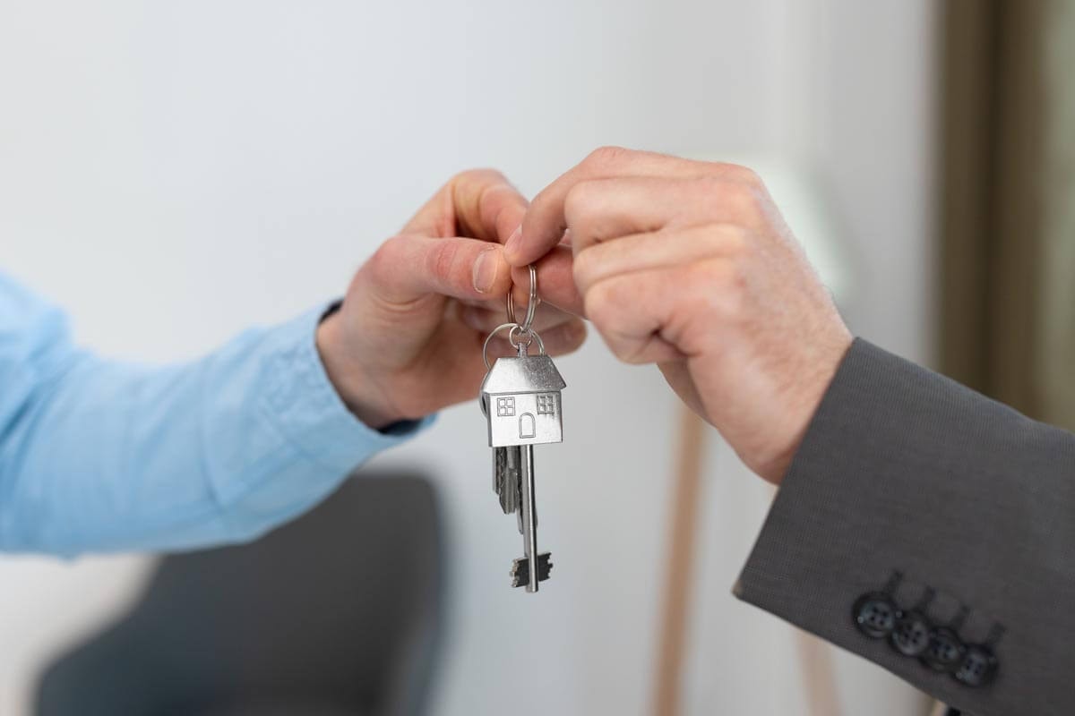 Two people holding a bunch of keys together; symbolic image of the handover of keys between an estate agent and a new tenant.