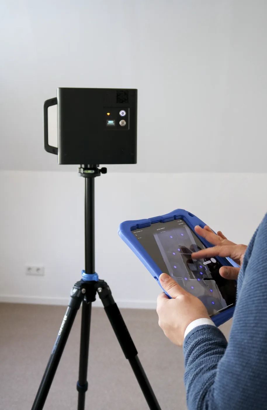 Hand holding a laser distance measurer against a wall