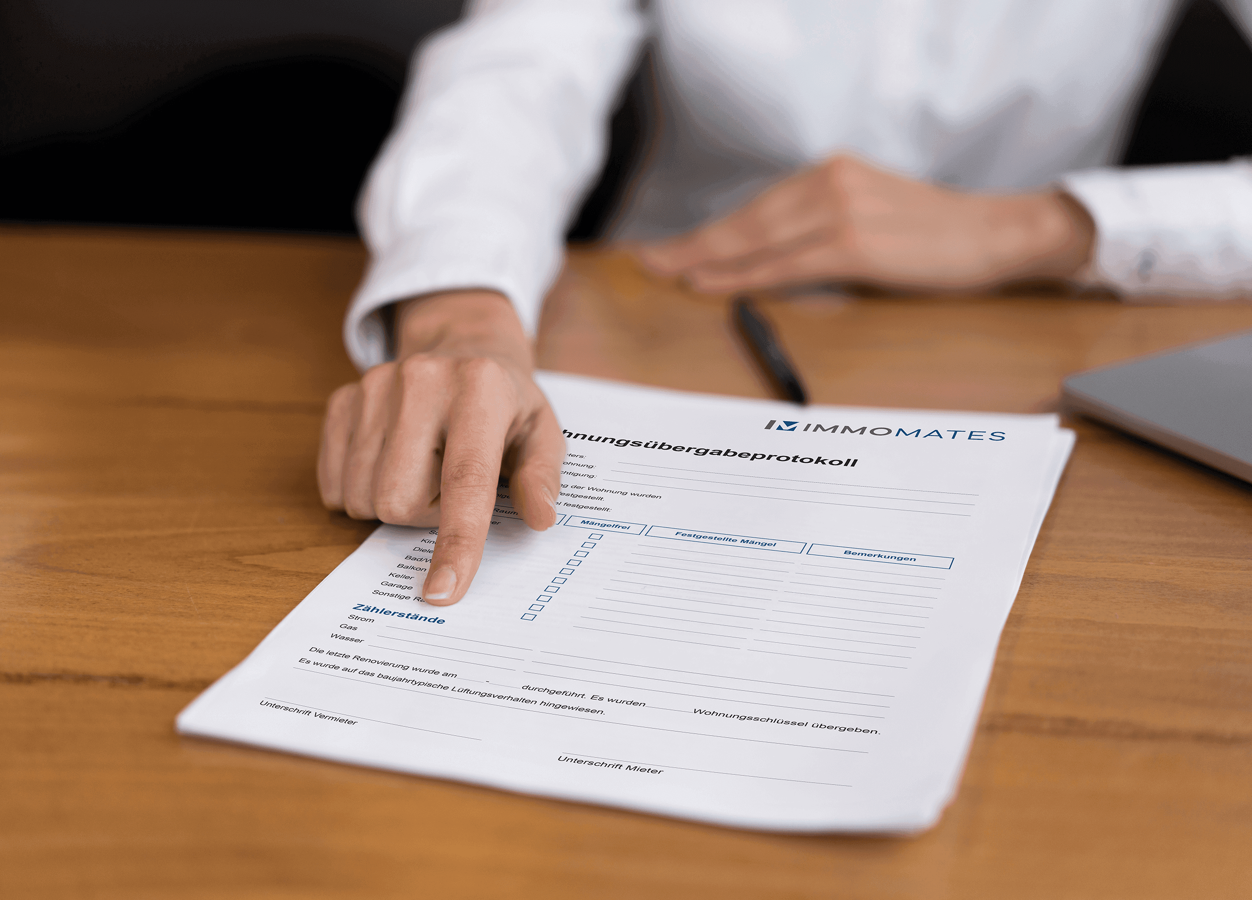 Close-up of a person at a desk with a property handover protocol in front of them, pointing to the section where the meter readings are to be noted.