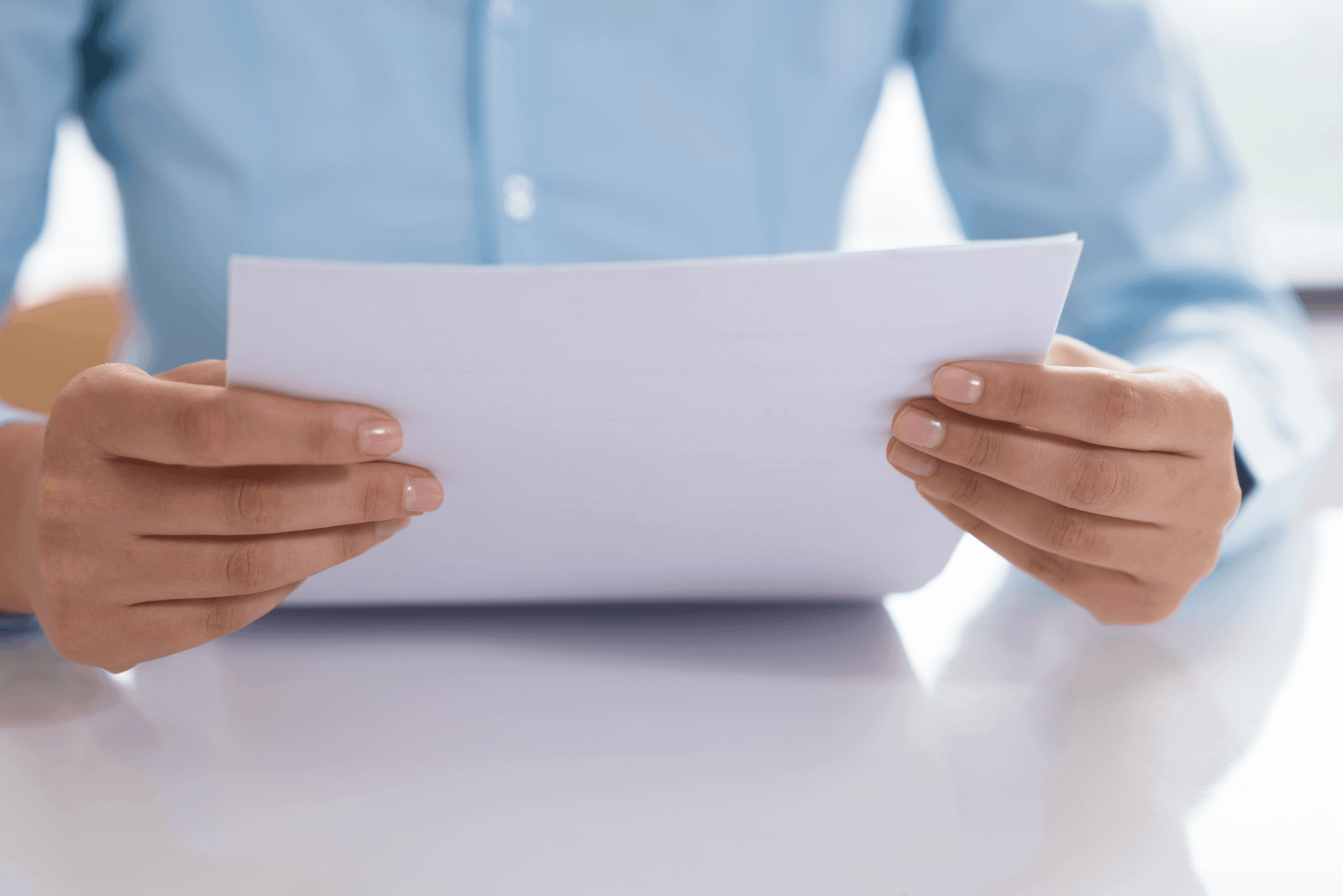 Front close-up of two arms holding up a document.