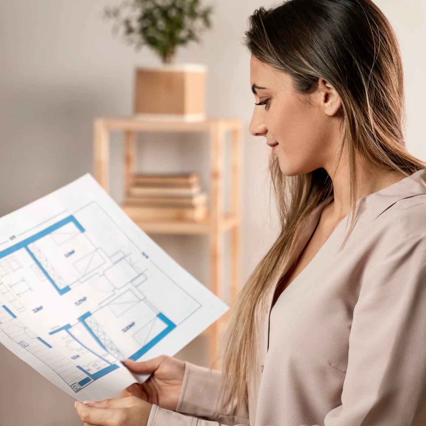 Side-on shot of a woman looking at a floor plan in her hand.