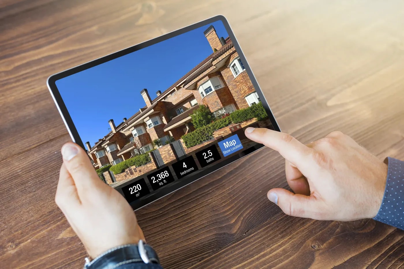 Jemand betrachtet das Aussenfoto eines Reihenhauses in einer Immobilienapp im Tablet.
