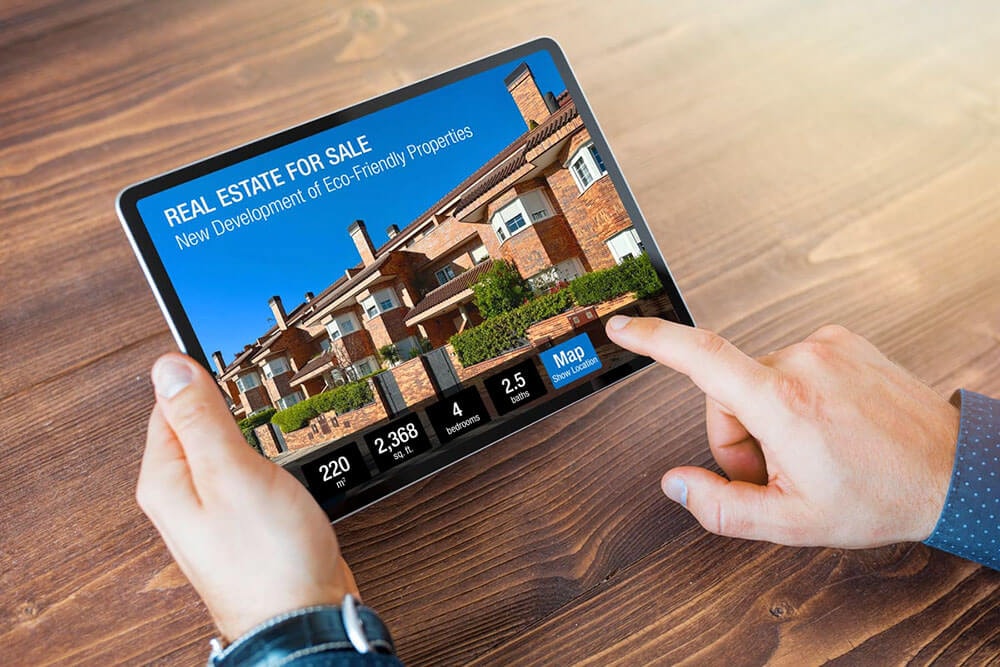 Someone looks at an exterior photo of a terraced house in a real estate app on a tablet