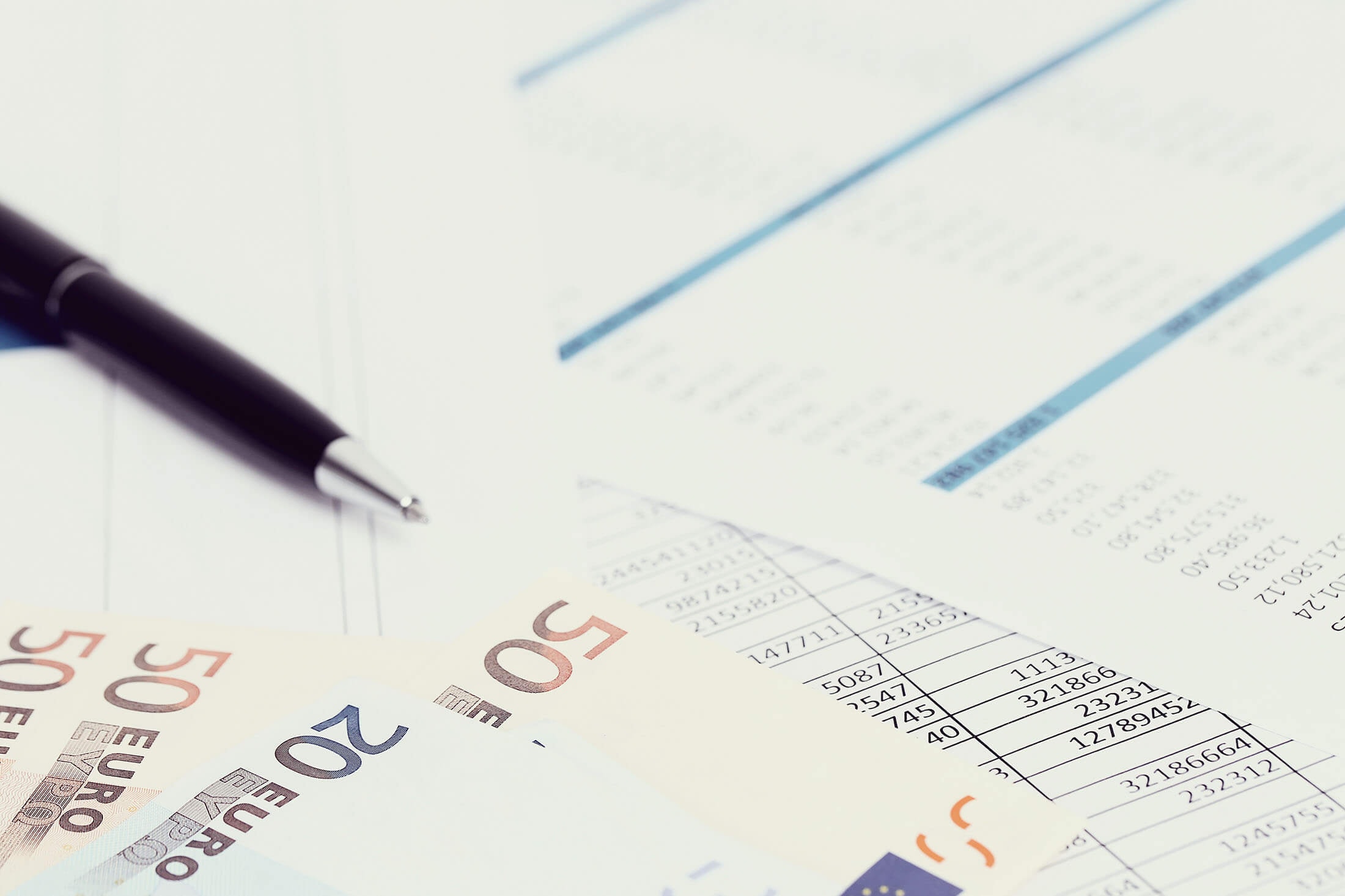 Close-up of tax documents, a pen, a twenty-euro note, and three fifty-euro notes