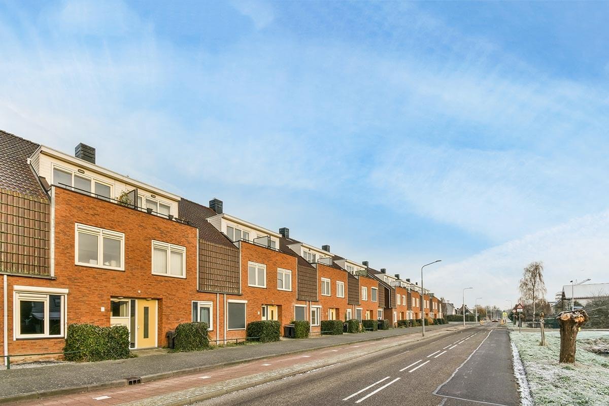 An ageing terraced house with a clinker brick facade, large windows and a mansard roof including a mansard storey.