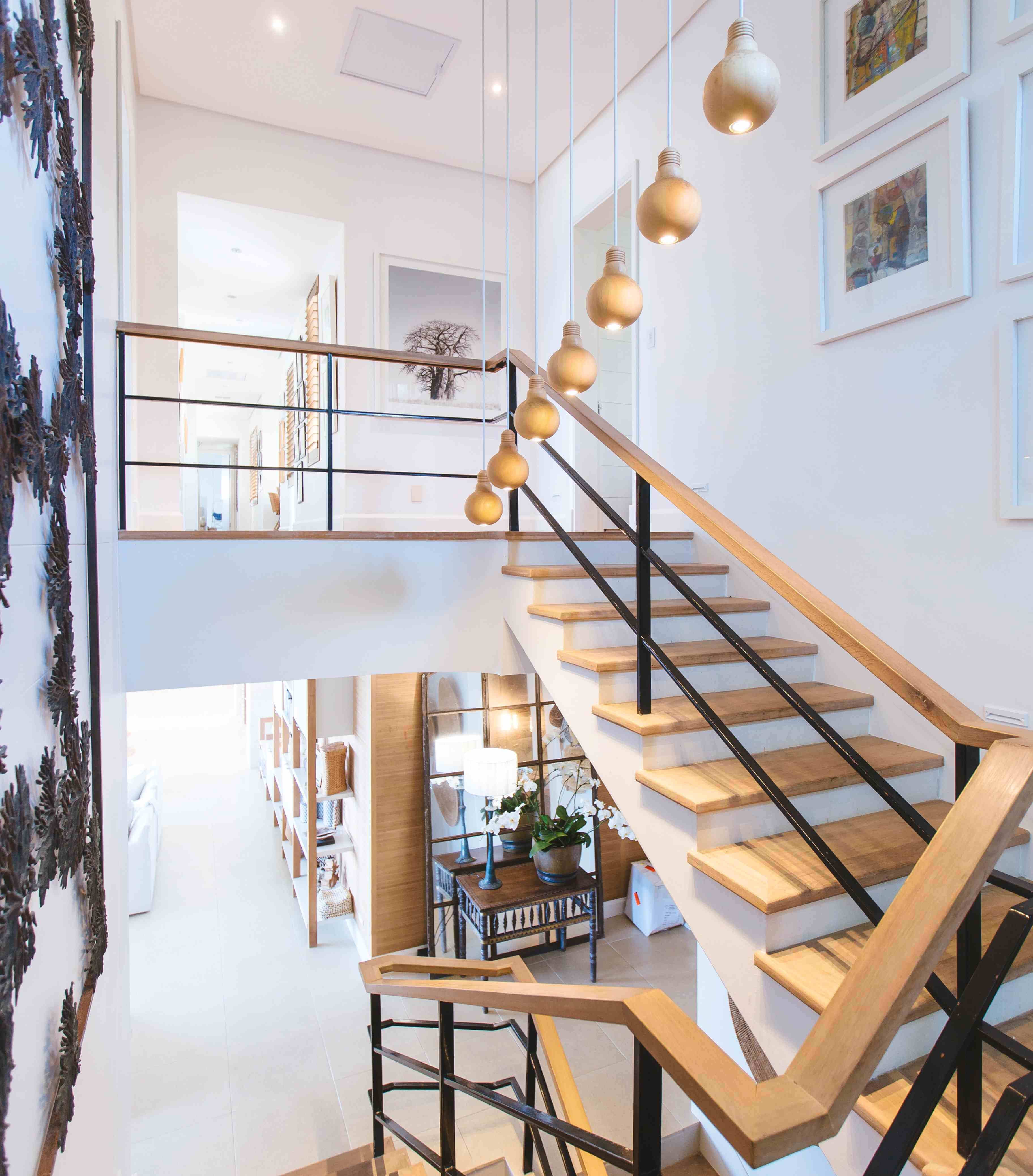 View from the mezzanine level looking at the upper part of a staircase leading to the upper floor, past a row of ceiling lights with wooden fittings and a brief glimpse into the floor below.