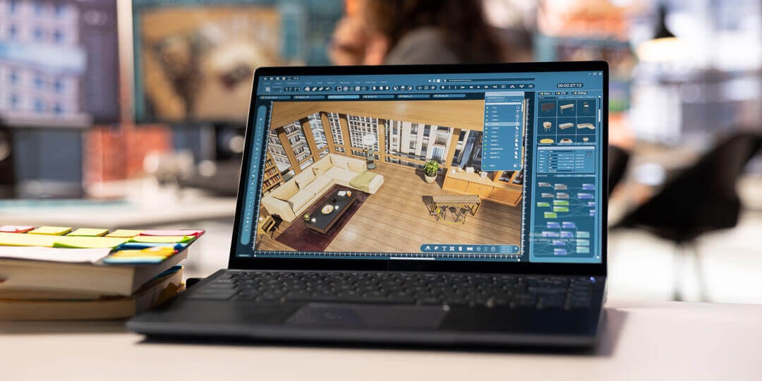 3D view of a digitally created living room on a laptop screen, standing next to two stacked books on a desk with an office setting in the background.