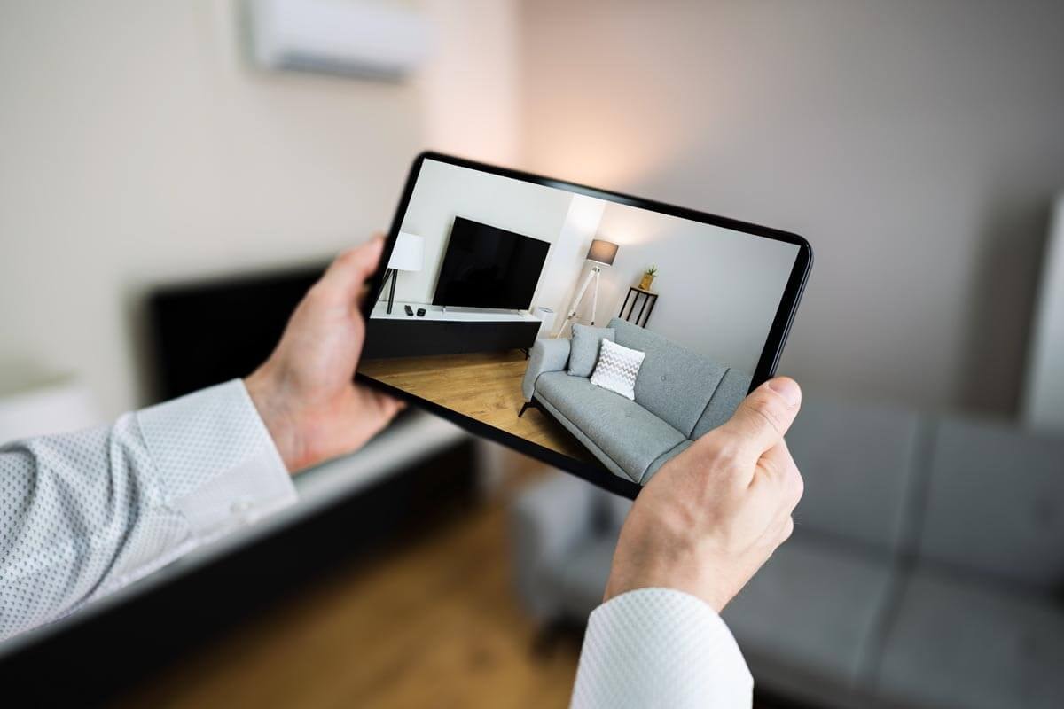 A person takes a photo of the living room using a tablet held up with both hands