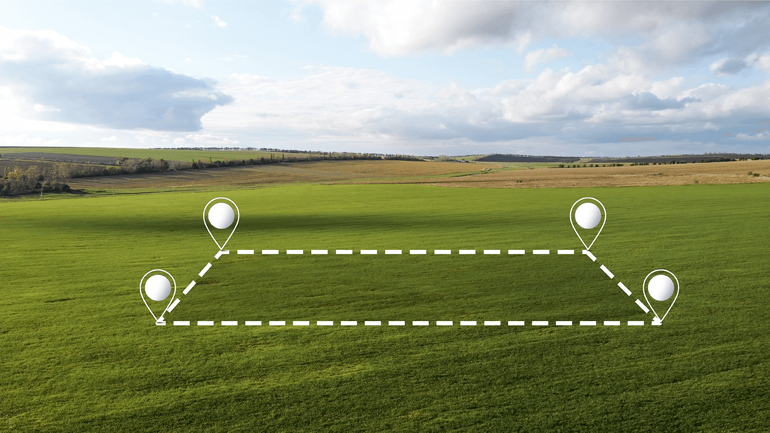 Photo of a large meadow on which the rough outline of a rectangular plot is indicated with white dashed lines, with white pins marking the corners.