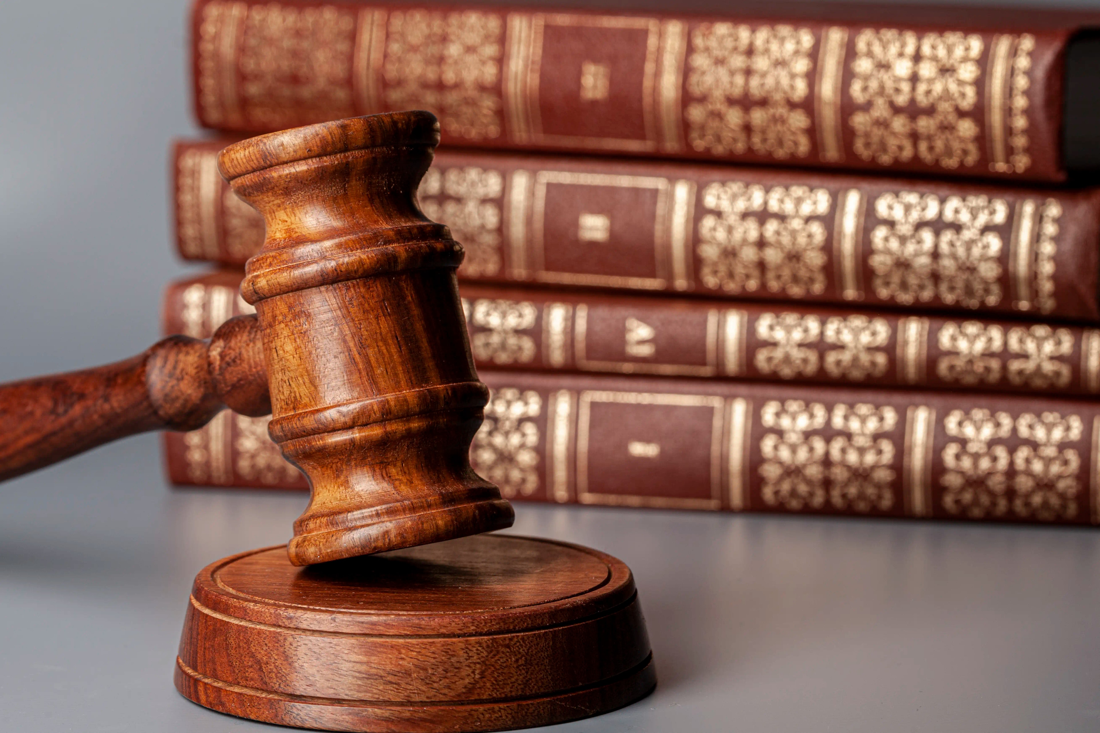 Close-up of a judge's gavel in front of Roman-numbered law books.