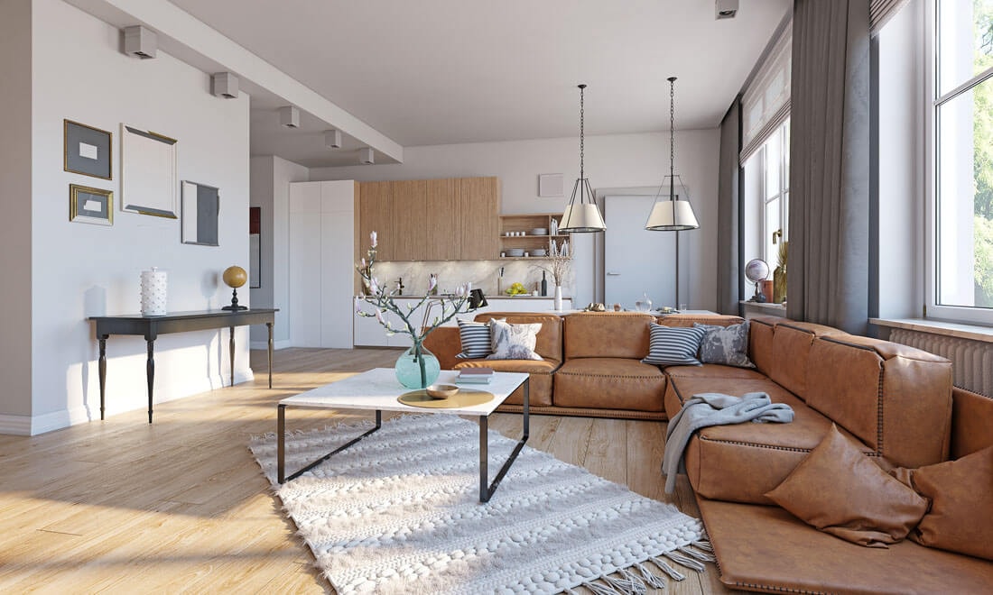 Open-plan living and kitchen area with a large brown leather corner sofa, white marble coffee table and a modern kitchen with wood and white fronts in the background.